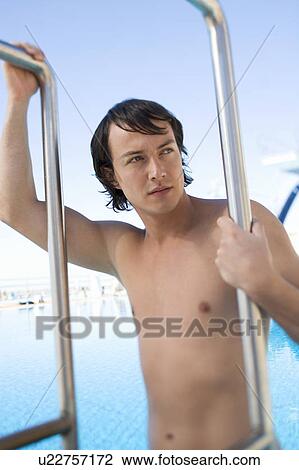 A young man climbing into a swimming pool View Large Photo Image Stock Image - A young man climbing into a swimming pool. Fotosearch