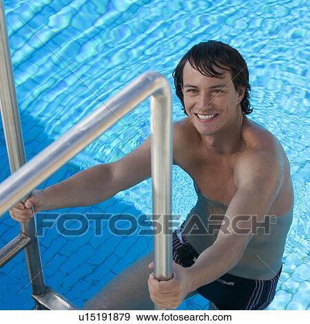 Stock Photo - A young man climbing into a swimming pool. Fotosearch
