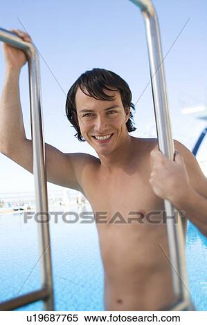 A young man climbing into a swimming pool View Large Photo Image Stock Photography - A young man climbing into a swimming pool. Fotosearch