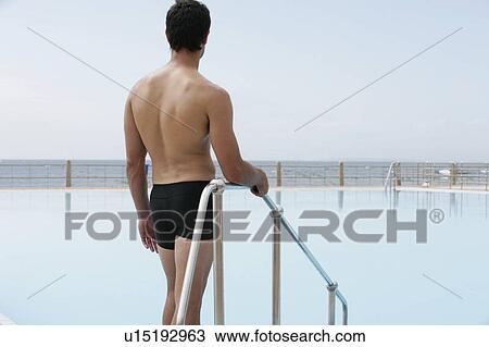 A young man standing by a swimming pool View Large Photo Image Stock Image - A young man standing by a swimming pool. Fotosearch