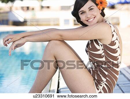 A young woman sitting by a swimming pool View Large Photo Image Stock Image - A young woman sitting by a swimming pool. Fotosearch