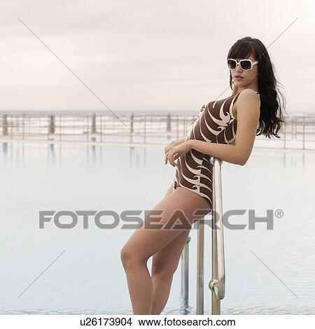 A young woman standing by a swimming pool View Large Photo Image Picture - A young woman standing by a swimming pool. Fotosearch