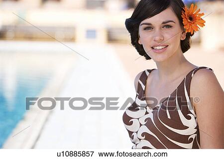 A young woman standing by a swimming pool View Large Photo Image Stock Photo - A young woman standing by a swimming pool. Fotosearch