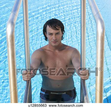 Stock Image - Portrait of a young man climbing into a swimming pool . Fotosearch