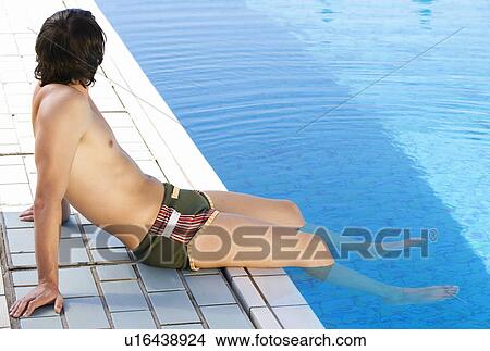 Young man relaxing by a swimming pool View Large Photo Image Picture - Young man relaxing by a swimming pool. Fotosearch