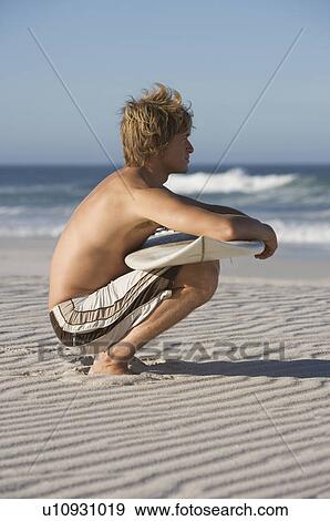 A surfer sitting on a beach View Large Photo Image Stock Photo - A surfer sitting on a beach. Fotosearch
