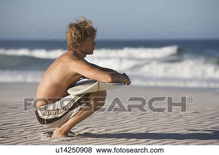 A surfer sitting on a beach View Large Photo Image Stock Photo - A surfer sitting on a beach. Fotosearch