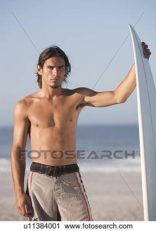 A surfer standing on a beach View Large Photo Image Stock Image - A surfer standing on a beach. Fotosearch
