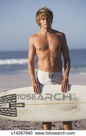 A surfer standing on a beach View Large Photo Image Stock Image - A surfer standing on a beach. Fotosearch