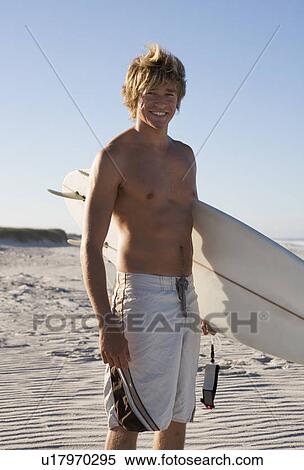 A surfer standing on a beach View Large Photo Image Stock Photography - A surfer standing on a beach. Fotosearch