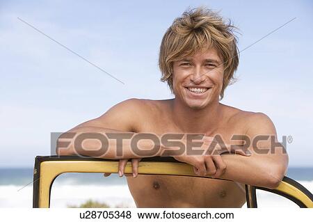A young man leaning on the door of a car View Large Photo Image Stock Photo - A young man leaning on the door of a car. Fotosearch
