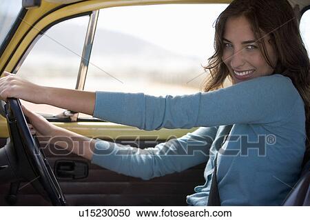 Stock Image - A young woman driving a car. Fotosearch
