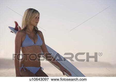Stock Photo - A young woman in a bikini with a surfboard. Fotosearch