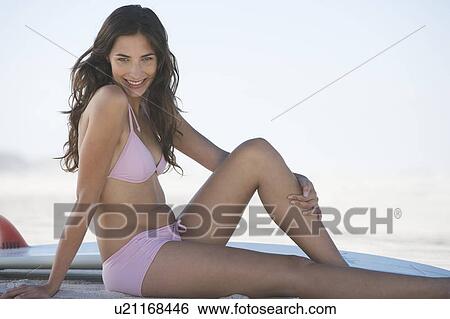 Stock Photograph - A young woman in a bikini with a surfboard. Fotosearch