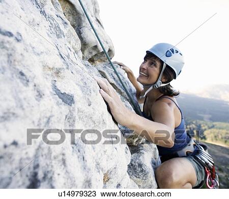 A climber climbing a rock face View Large Photo Image Stock Image - A climber climbing a rock face. Fotosearch
