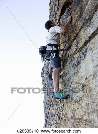 Stock Image - A climber climbing a rock face. Fotosearch