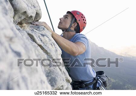 A climber climbing a rock face View Large Photo Image Stock Image - A climber climbing a rock face. Fotosearch