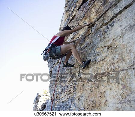 A climber climbing a rock face View Large Photo Image Stock Image - A climber climbing a rock face. Fotosearch