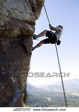 Stock Photo - A climber climbing a rock face. Fotosearch