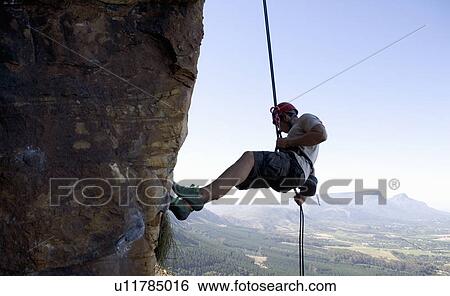 Stock Photograph - A climber climbing a rock face. Fotosearch