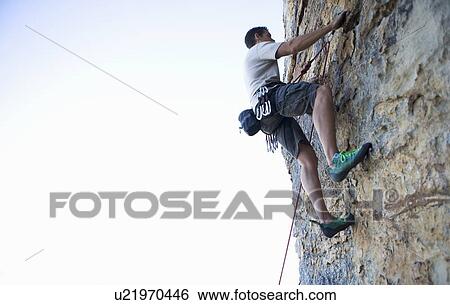 A climber climbing a rock face View Large Photo Image Stock Photograph - A climber climbing a rock face. Fotosearch