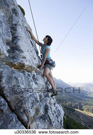 Stock Photograph - A climber climbing a rock face. Fotosearch