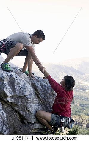 Stock Image - A climber helping another. Fotosearch
