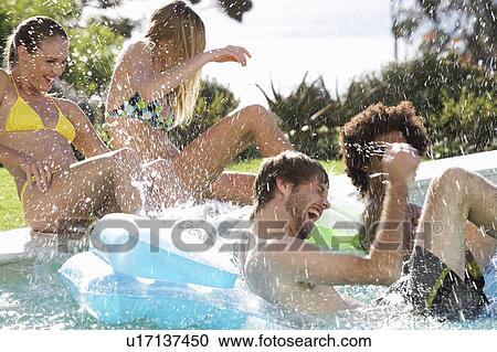 Stock Image - Four teenage friends having fun in a swimming pool. Fotosearch