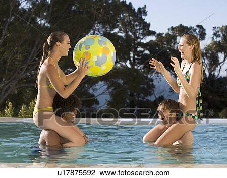 Stock Image - Four teenage friends having fun in a swimming pool. Fotosearch