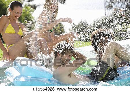 Stock Photograph - Four teenage friends having fun in a swimming pool. Fotosearch