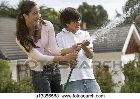 Stock Photo - A brother and sister playing with a hose pipe. Fotosearch
