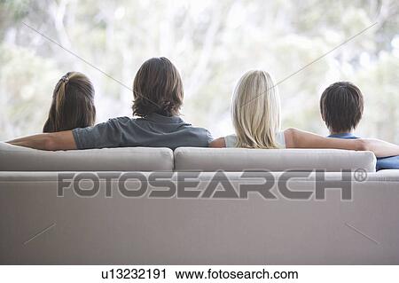 A family sitting on a sofa View Large Photo Image Stock Image - A family sitting on a sofa. Fotosearch