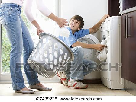 Stock Photography - A mother and son loading the washing machine. Fotosearch