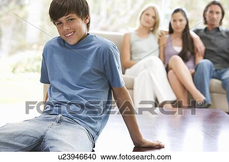 A young boy sitting on a coffee table with his family on the sofa View Large Photo Image Stock Image - A young boy sitting on a coffee table with his family on the sofa. Fotosearch
