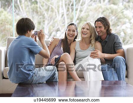 A young boy taking a photo of his family sitting on a sofa View Large Photo Image Stock Photo - A young boy taking a photo of his family sitting on a sofa. Fotosearch