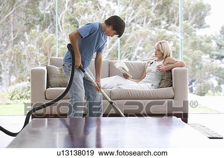 Stock Photo - A young boy vacuuming whilst his mother relaxes. Fotosearch