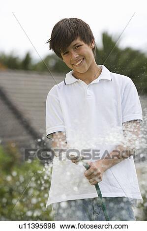 Stock Photo - A young boy watering the garden with a hose. Fotosearch