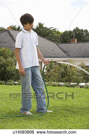 A young boy watering the garden with a hose View Large Photo Image Stock Photo - A young boy watering the garden with a hose. Fotosearch