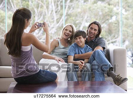 A young girl taking a photo of her family sitting on a sofa View Large Photo Image Picture - A young girl taking a photo of her family sitting on a sofa. Fotosearch