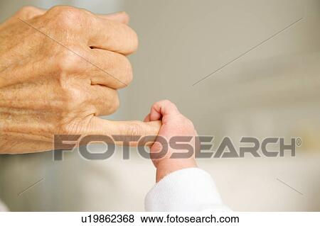 Stock Photo - A baby's hand holding their grandparent's finger. Fotosearch