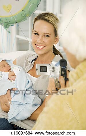 A grandmother videoing her daughter and new baby View Large Photo Image Picture - A grandmother videoing her daughter and new baby. Fotosearch