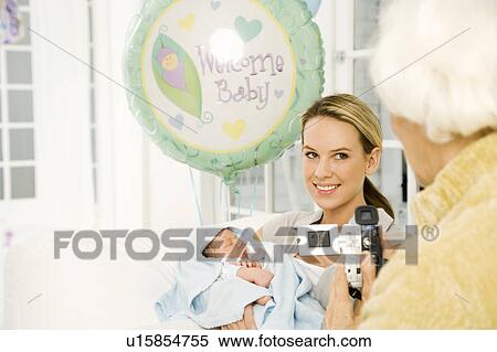 Stock Photography - A grandmother videoing her daughter and new baby. Fotosearch