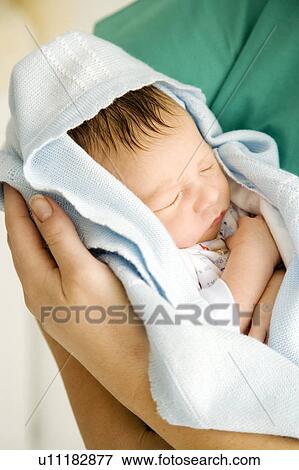Stock Photo - A medical practitioner holding a newborn baby. Fotosearch