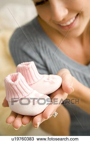 Stock Image - A mother holding a pair of baby bootees. Fotosearch