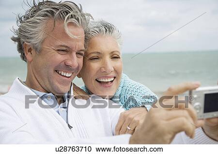 A senior couple on a beach taking a picture with a digital camera View Large Photo Image Stock Image - A senior couple on a beach taking a picture with a digital camera. Fotosearch