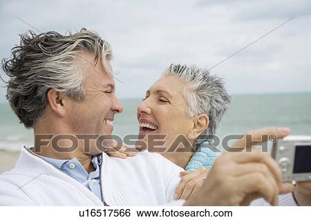 A senior couple on a beach taking a picture with a digital camera View Large Photo Image Stock Photograph - A senior couple on a beach taking a picture with a digital camera. Fotosearch