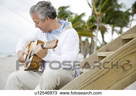 Stock Image - A senior man playing a guitar. Fotosearch