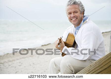 Stock Image - A senior man playing a guitar. Fotosearch