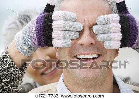 Stock Image - A senior woman surprising her partner. Fotosearch