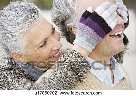 Stock Image - A senior woman surprising her partner. Fotosearch